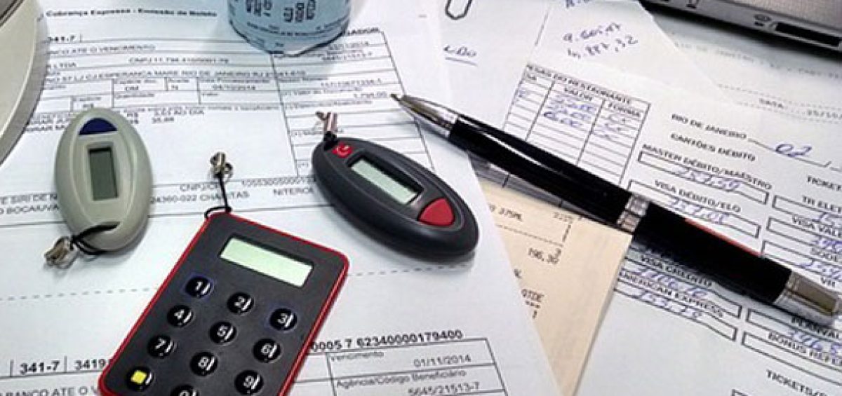 Riscos do registro de moeda funcional no programa SPED Contábil com documentos fiscais, calculadora e tokens de segurança em mesa de escritório