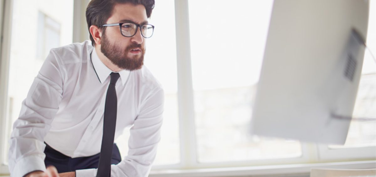 Homem de negócios analisando informações no computador, representando pontos de atenção no sistema Siscoserv e sua importância para a gestão tributária e fiscal das empresas
