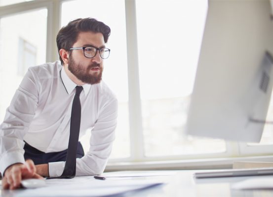 Homem de negócios analisando informações no computador, representando pontos de atenção no sistema Siscoserv e sua importância para a gestão tributária e fiscal das empresas