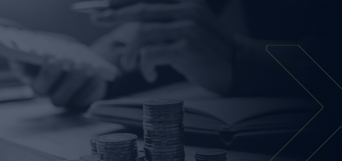 Pilhas de moedas em foco com pessoa ao fundo usando calculadora e caderno aberto, ilustrando planejamento estratégico para alcançar equilíbrio financeiro.