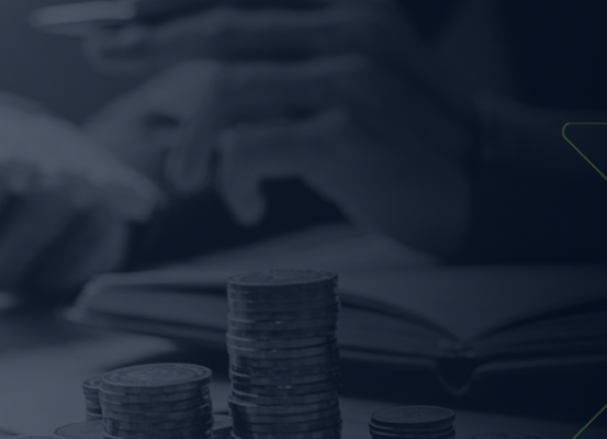 Pilhas de moedas em foco com pessoa ao fundo usando calculadora e caderno aberto, ilustrando planejamento estratégico para alcançar equilíbrio financeiro.