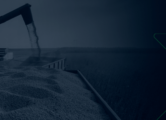 Colheita agrícola com máquina agrícola transferindo grãos para caminhão, representando o protagonismo do agronegócio com a IN 2.121/2022.