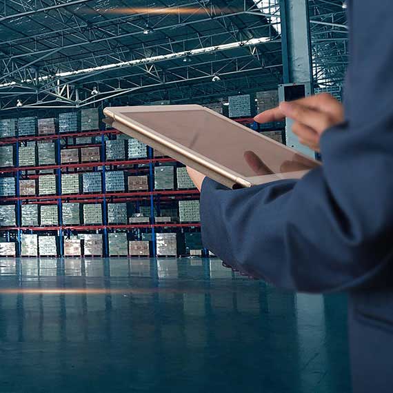 Profissional utilizando tablet para gerenciar catálogo de produtos na Duimp em armazém industrial