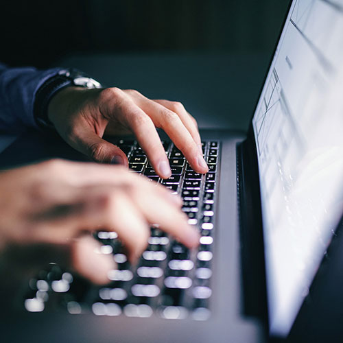 Mãos digitando em notebook para preenchimento da EFD-Reinf, obrigação acessória do SPED que registra retenções e contribuições previdenciárias.