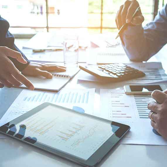 Profissionais analisando gráficos e relatórios fiscais em reuniões, com tablet e calculadora, representando a apuração e gestão da EFD-Reinf