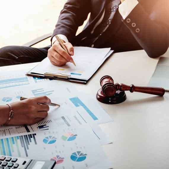 Profissionais analisando gráficos financeiros e documentos jurídicos com martelo de juiz sobre a mesa, representando a aplicação do Ex-Tarifário na gestão tributária e redução de custos de importação