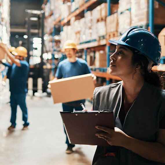 Gestão de fretes e estoque fiscal em terceiros: profissionais em armazém logístico realizando conferência de cargas e mercadorias.