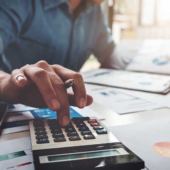 Profissional calculando desempenho de imposto de importação com planilhas e calculadora, ilustrando análise tributária e performance fiscal