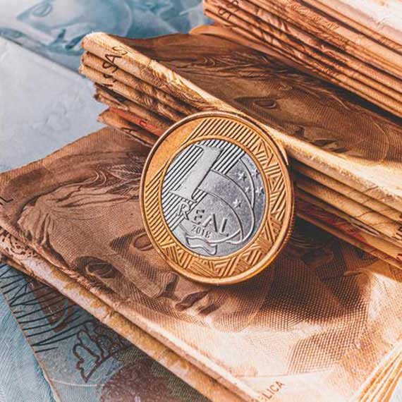 Moeda de um real em destaque sobre notas de reais, simbolizando o programa Reintegra e os benefícios fiscais para empresas exportadoras no Brasil.