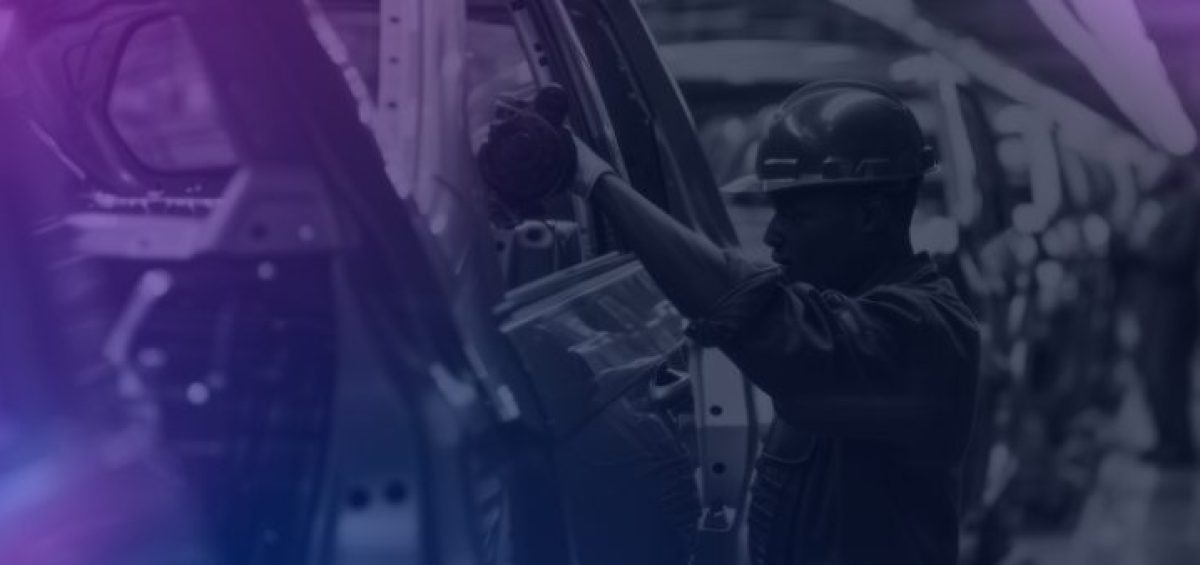 Trabalhador em uma linha de montagem industrial, utilizando equipamentos de proteção enquanto realiza a montagem da carroceria de um automóvel em uma fábrica, simbolizando a crescimento na produção de autoveículos em 2025.